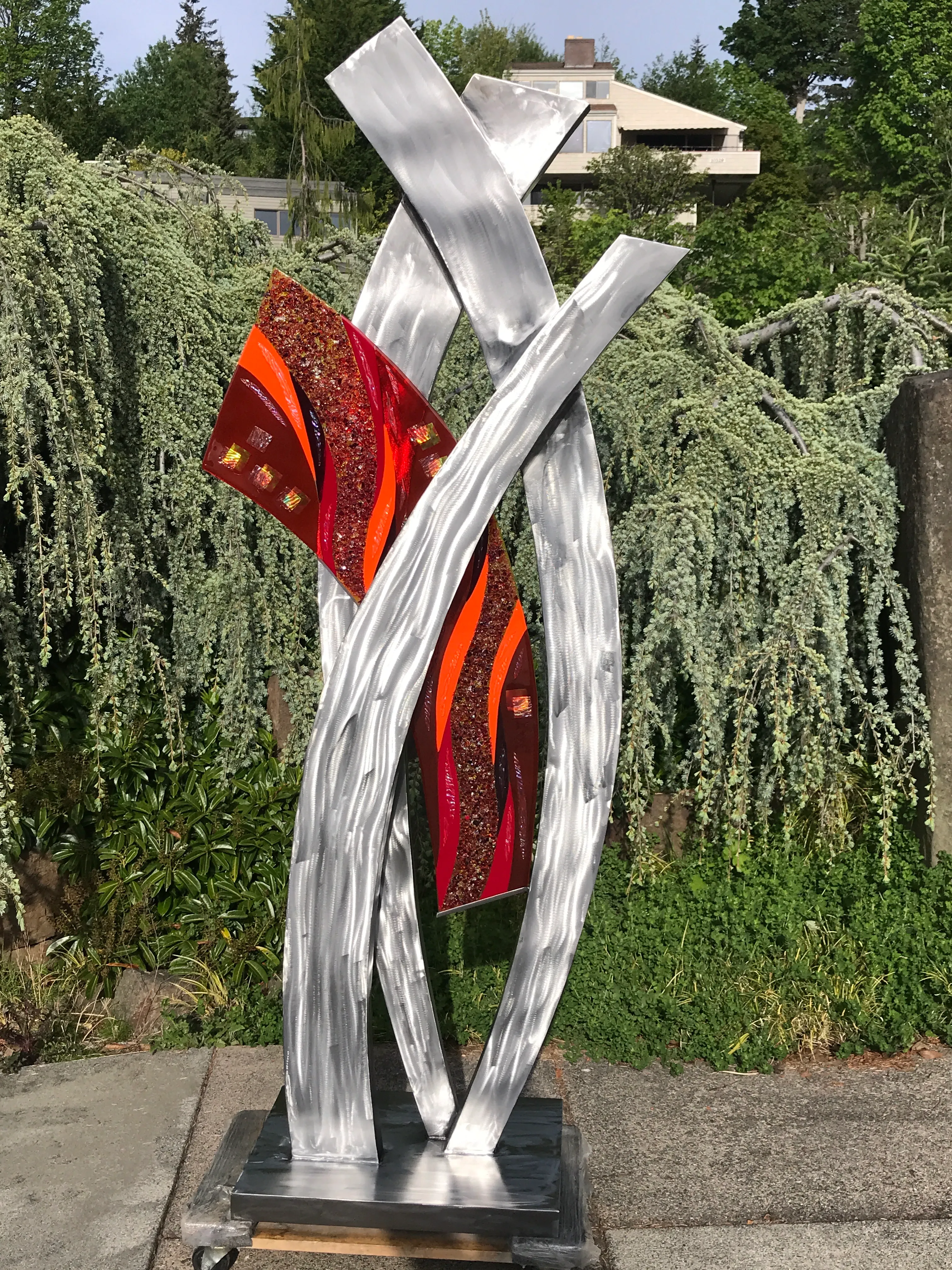 Collaborative sculpture with sweeping metal curves and glass inlay
